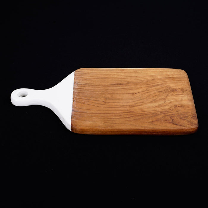 Side view of square shaped teak cutting board/serving platter with white handle displayed horizontally on a black background