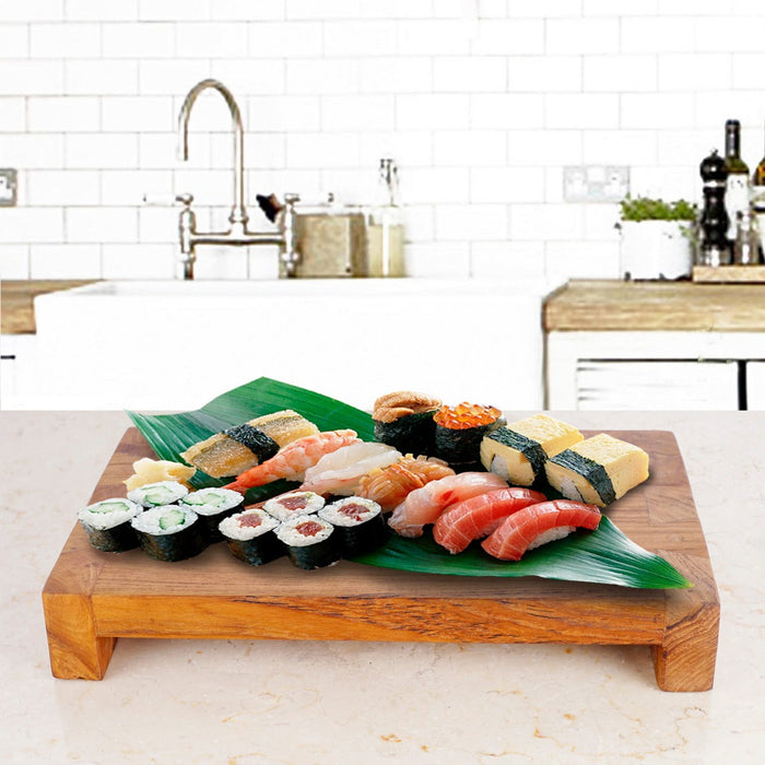 Rico & Plato wasabi teak serving platter with an assortment of sushi on top displayed on a light colored granite countertop in a kitchen setting