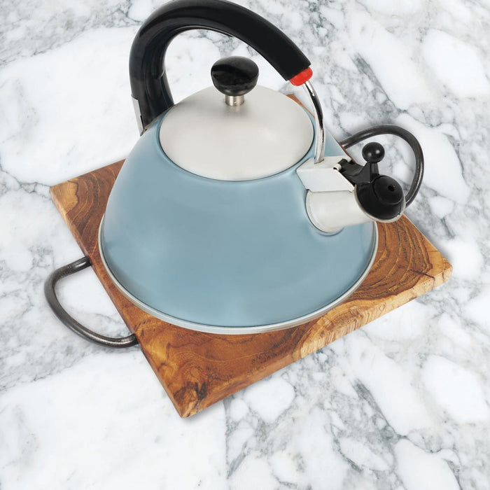 A teak wood trivet with curved steel handles, with a blue and white kettle on top of it, placed on a marble surface.