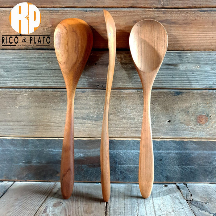 Three teak wood spoons placed by each other to view the back, side, and front view on a wooden background