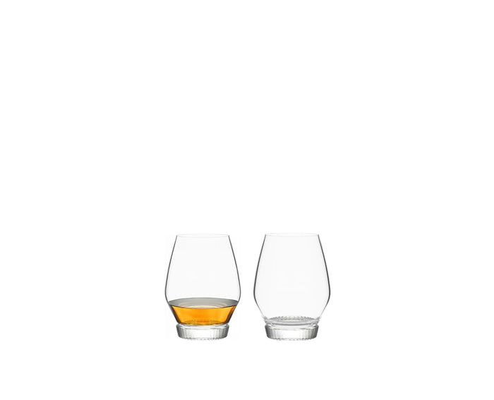 Two bourbon glasses, one filled with a amber liquid, on a white background