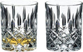 Two Riedel Fine Crystal Tumblers spey whisky with a geometric pattern, one with a small amount of amber-colored liquid, likely whisky, and the other empty
