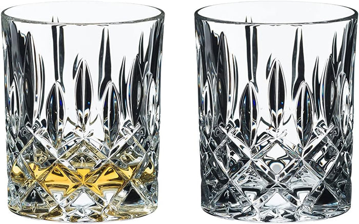 Two Riedel Fine Crystal Tumblers spey whisky with a geometric pattern, one with a small amount of amber-colored liquid, likely whisky, and the other empty