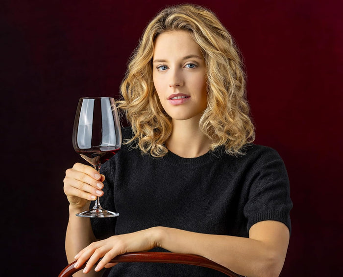 Woman holding a glass of red wine against a dark background