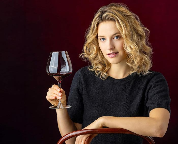 Woman holding a glass of red wine against a dark background