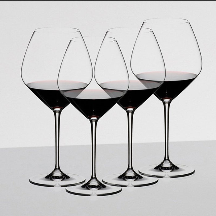 Four Riedel Pino Noir wine glass with red wine inside all on a white background