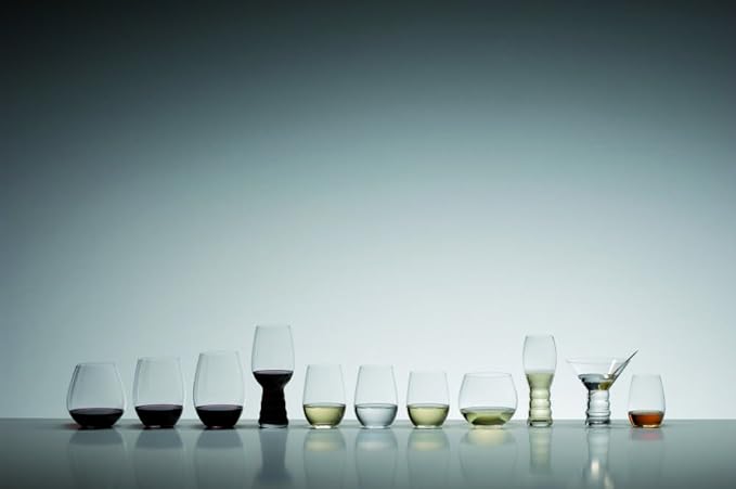 An assortment of Riedel wine tumbler viognier chardonnay with red wine, white wine, brown liquid, or white liquid inside the glasses on a white background and reflective surface