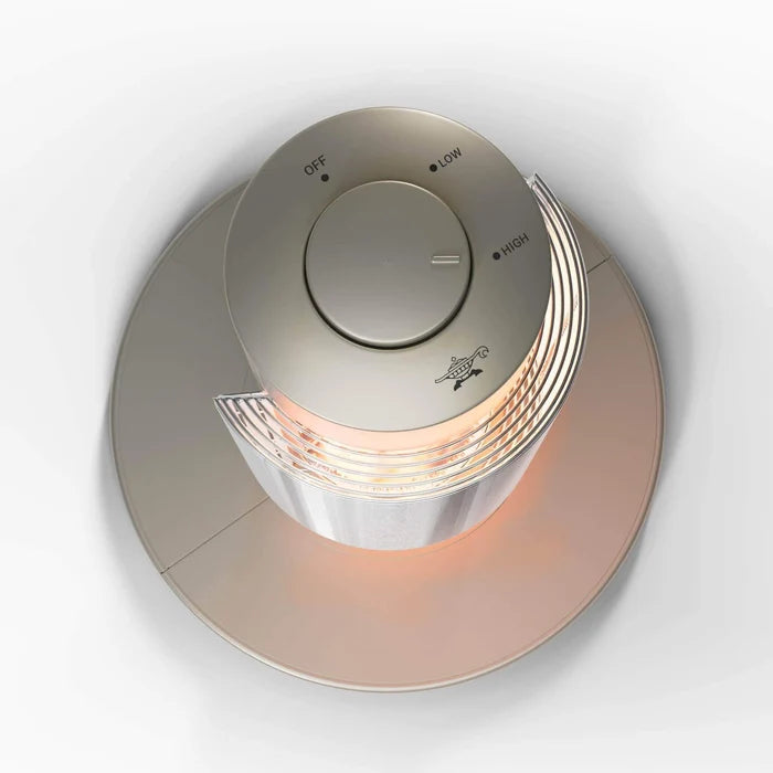 A modern circular electric heater with a metallic champagne top control panel, featuring 'OFF', 'LOW', and 'HIGH' settings, and a glowing orange interior visible through a ribbed lower section, set against a clean white background.