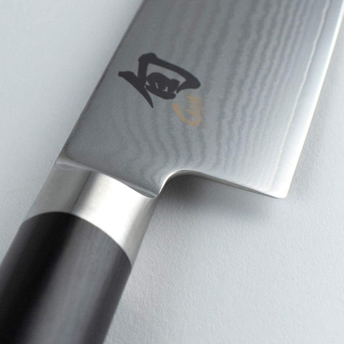 Close up of hilt of Shun Classic Master Utility 6.5″ displayed on a white background