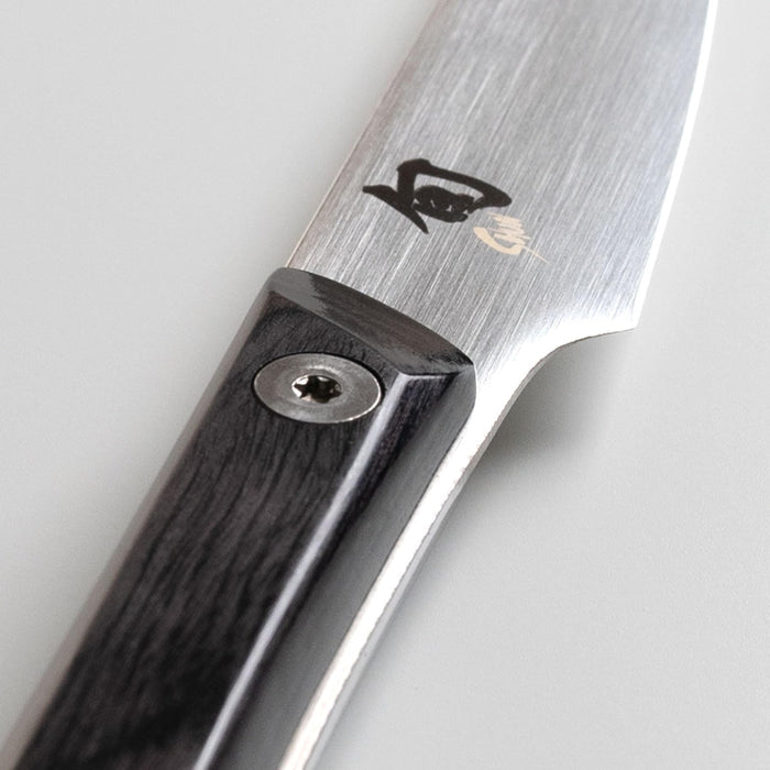 Close up of the hilt of a Shun paring knife on a white background
