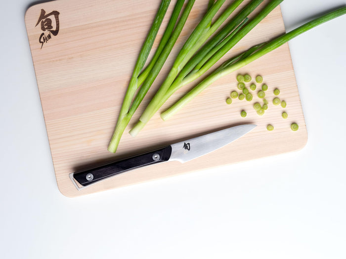 3.5 inch Shun paring knife on a Shun cutting board with green onions and chopped green onions
