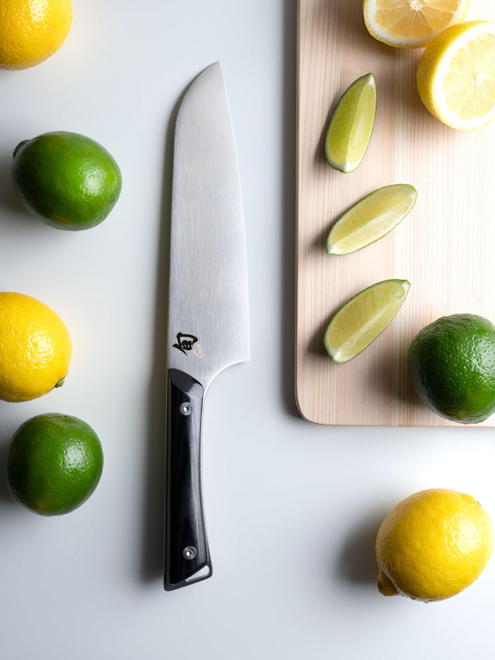 7 inch Shun santoku knife on a white countertop next to lemons and limes