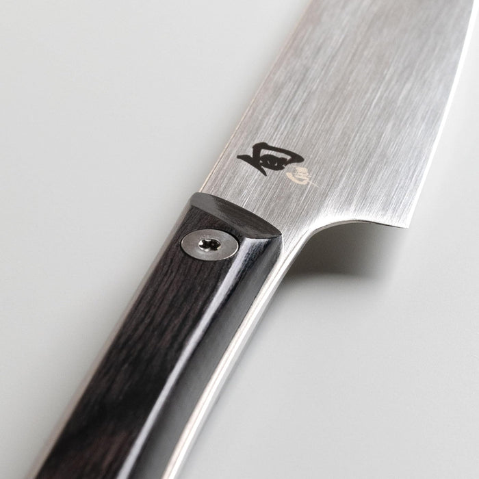 Close up of the hilt of a Shun utility knife on a white background