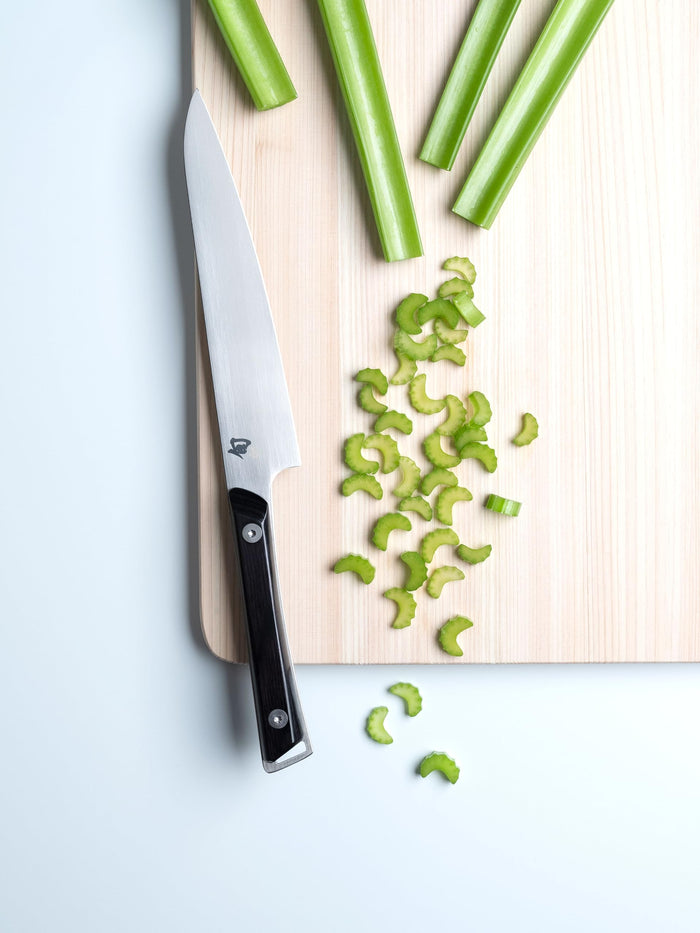 6 inch Shun utility knife on a cutting board with celery stick and chopped celery