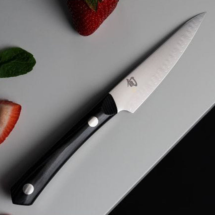 4 inch paring knife next to strawberries displayed on a white countertop