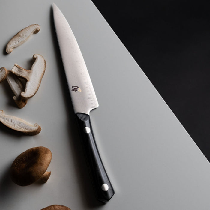 6 inch utility knife displayed next to sliced mushrooms on a white countertop