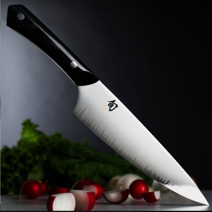 Chef knife with sliced vegetables in the background