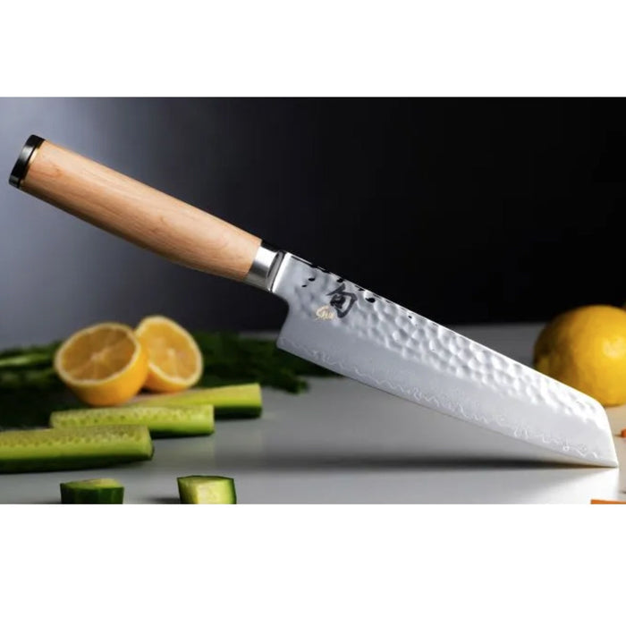 6.5 inch Shun premier utility knife with a blonde handle with sliced vegetables in the background