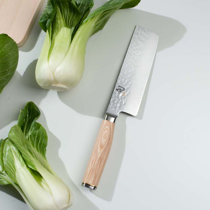 5.5 inch Shun premier nakiri knife with blonde handle next to bok choy on a white background