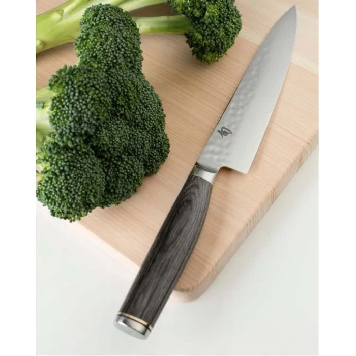 6.5 inch utility knife next to broccoli on a cutting board displayed on a white countertop