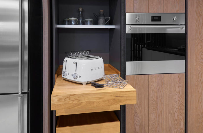 Kitchen interior with a toaster on a wooden counter, stainless steel refrigerator, and oven.