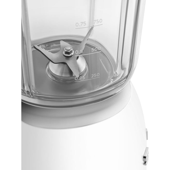 Close-up of a blender's clear container with measurement markings and silver blade on a white background.