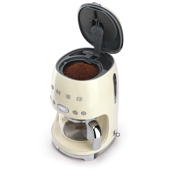 Top view of cream Smeg coffee machine with top open with a view of grounded coffee beans on a white background