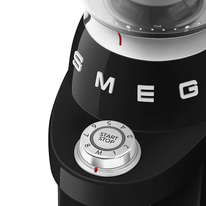 Black SMEG coffee grinder with control knob and brand logo on a white background