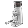 A SMEG 50's Retro Style Electric Espresso Coffee Grinder in silver color, featuring a conical burr mill and a digital display.
