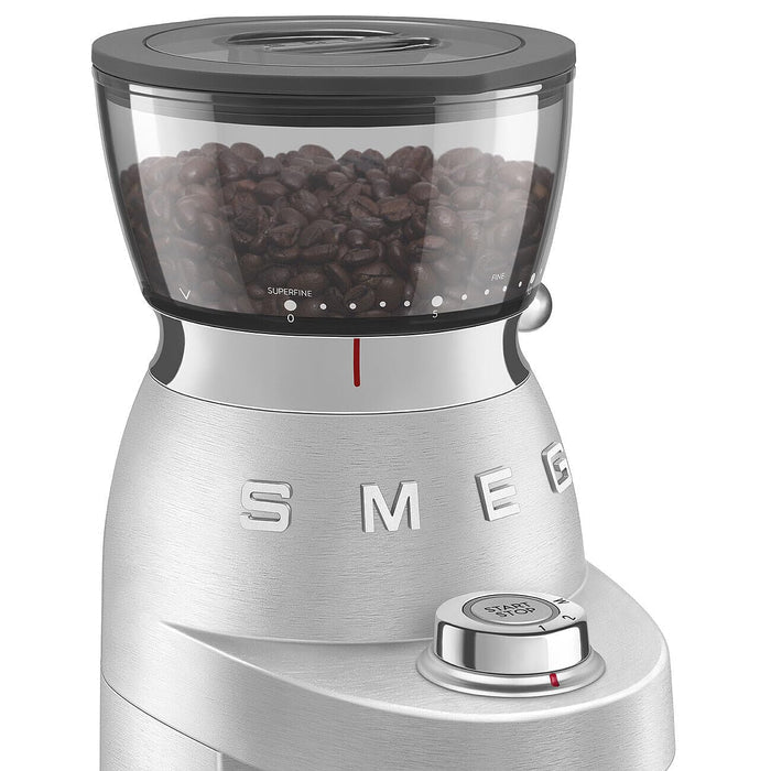 Close up of the stainless steel Smeg retro style electric espresso coffee grinder of the control dial and where the coffee beans stored on a white background