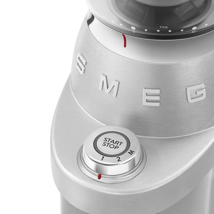 Close up of the control dial on the stainless steel Smeg retro style electric espresso coffee grinder on a white background
