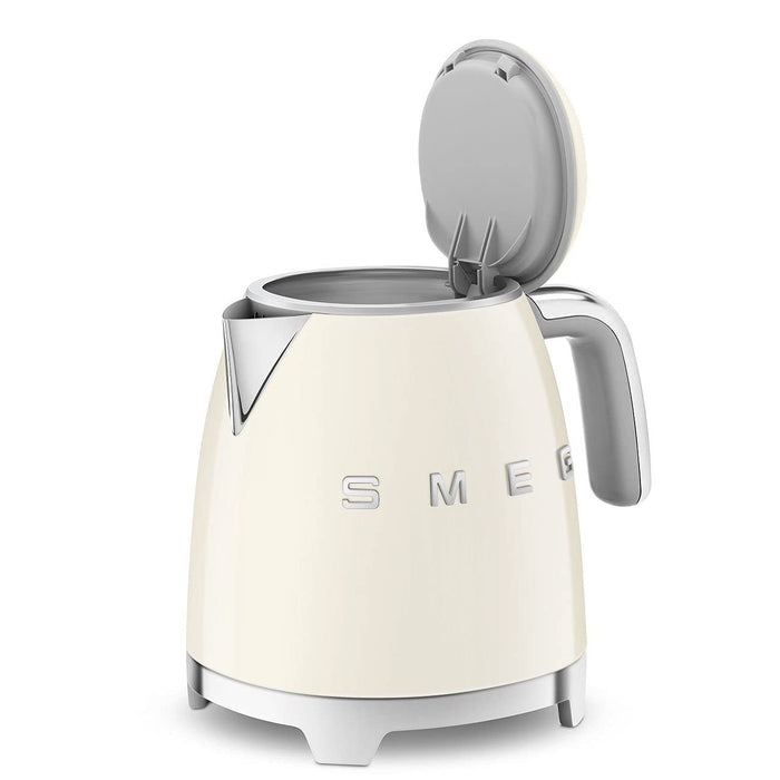 Smeg cream-colored kettle with metallic accents and lid open on a white background