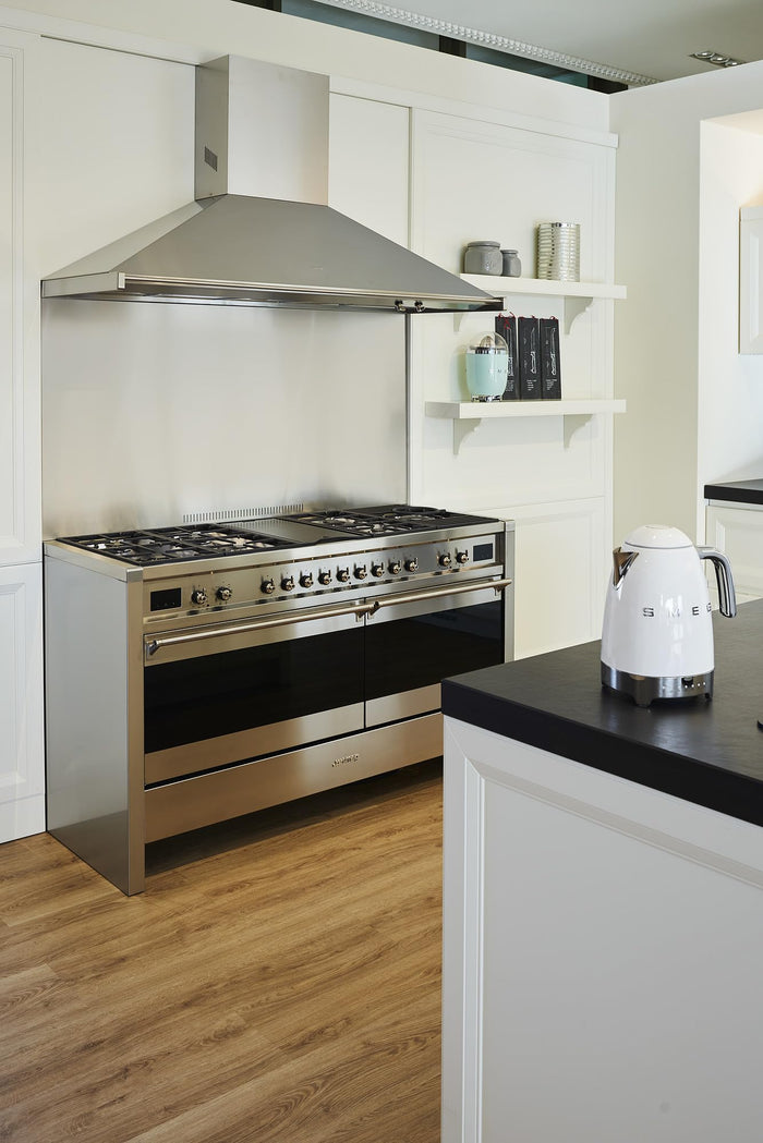 Modern kitchen with stainless steel stove and black countertop with a white Smeg electric kettle