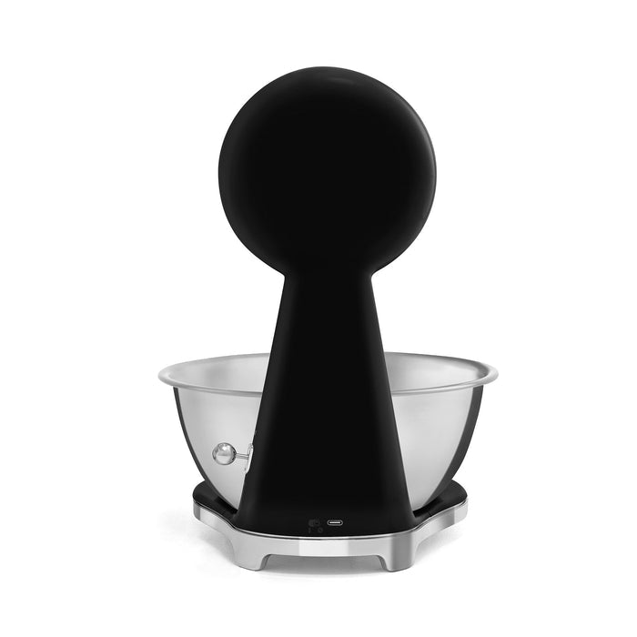 Back view of a black, silver Smeg retro style analog digital kitchen scale on a white background