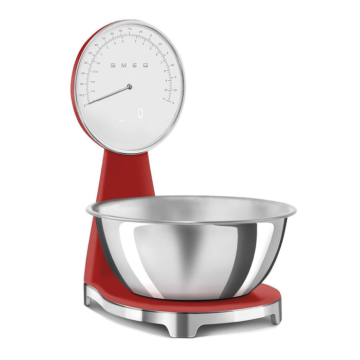 Front of a red Smeg retro style analog digital kitchen scale with a silver bowl on a white background