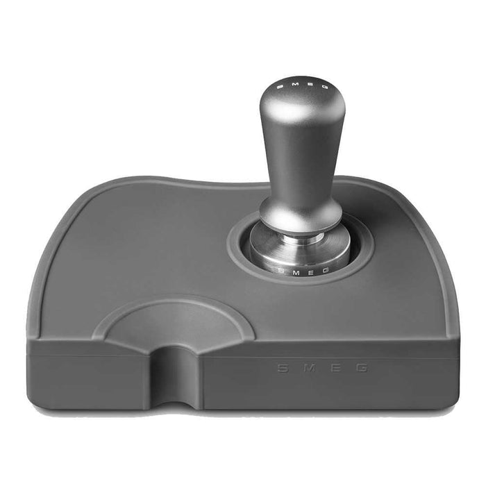 Grey, stainless steel Smeg tamper and portafilter holder with a stainless steel Smeg tamper in tamper spot on a white background