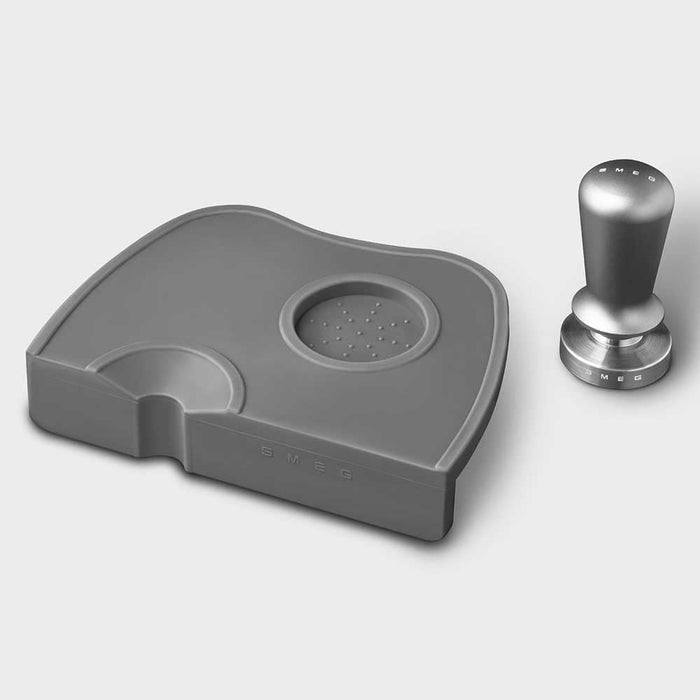 Grey, stainless steel Smeg tamper and portafilter holder with Smeg stainless steel tamper on the side on a white background