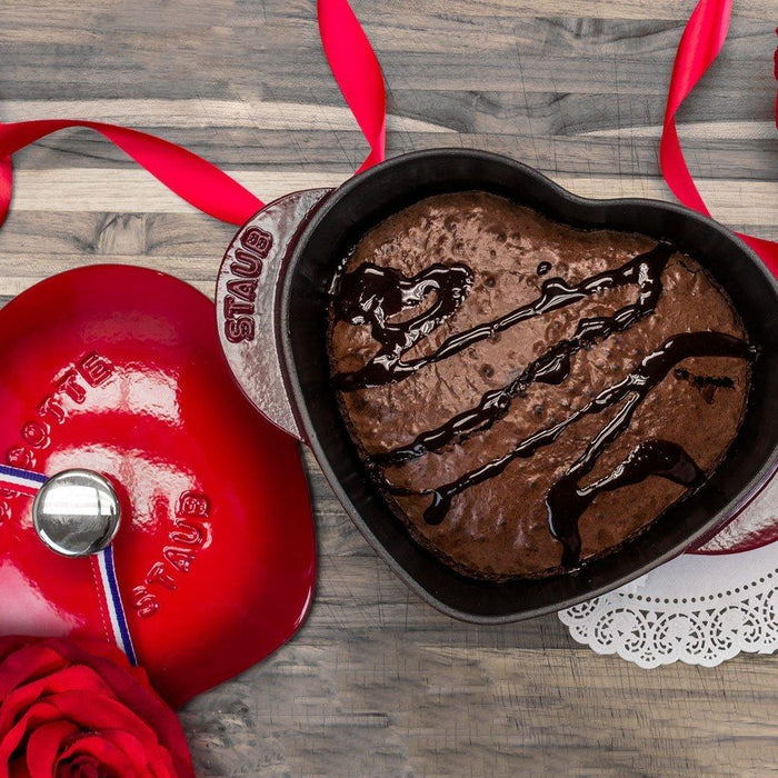 Staub Cast Iron 1.75-qt Heart Cocotte - Cherry with brownie and hot fudge inside with lid on the side displayed on a wooden surface