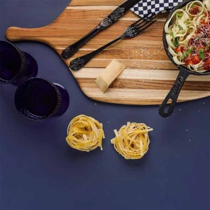Teakhaus large canoe paddle cutting board with materials for pasta making on a purple surface