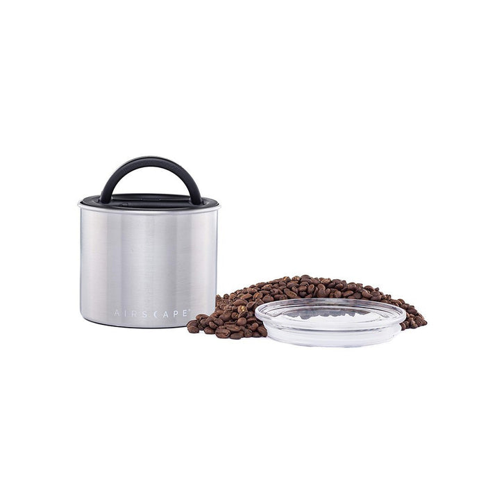 Brushed steel coffee canister with lid, coffee beans, and a clear container on a white background