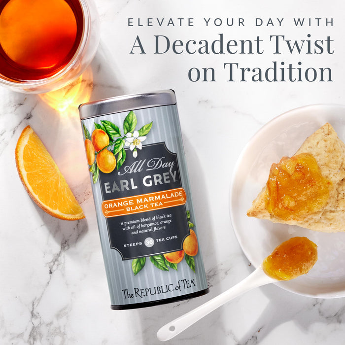 Tea canister labeled 'All Day Earl Grey' with a cup of tea, orange slice, and scone on a marble surface.