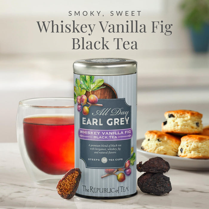 Tea canister labeled 'All Day Earl Grey Whiskey Vanilla Fig Black Tea' with a glass of tea and biscuits in the background.