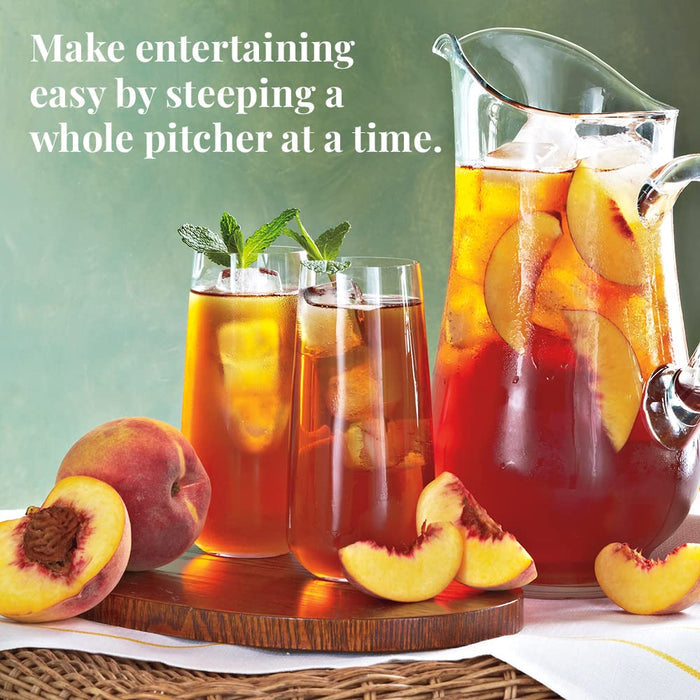 Peach iced tea with a pitcher and glasses on a wooden tray, surrounded by peaches.