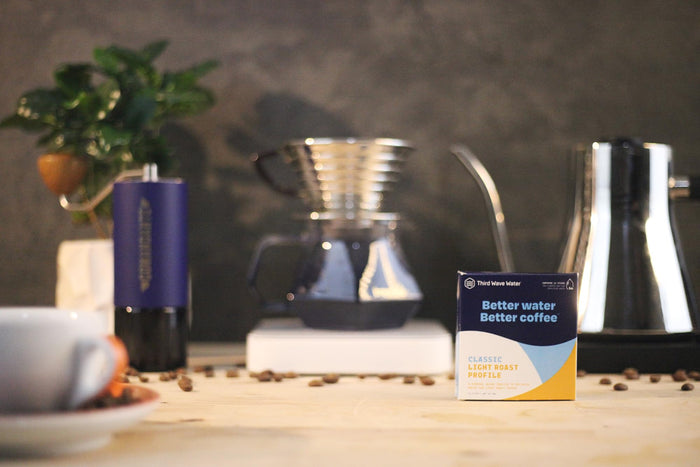 Coffee-making setup with a box of Third Wave Water Classic Light Roast Profile on a wooden surface.
