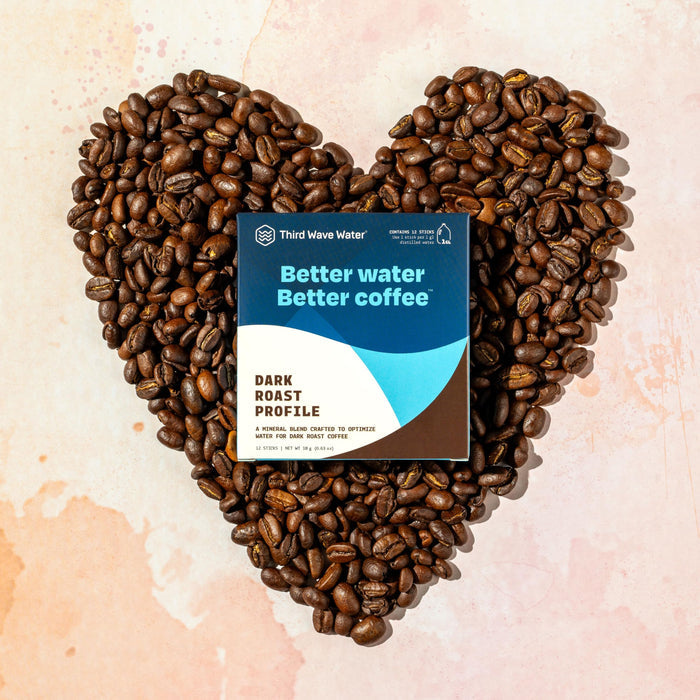 Heart-shaped arrangement of coffee beans with a Third Wave Water package on a light background