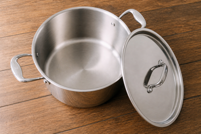 Stainless steel pot with lid on a wooden surface