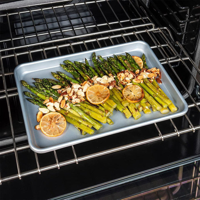 Viking Nonstick Baking Sheet Pan, Aluminized Steel, 0.88 mm Gauge with cooked lemons, nuts, and asparagus in an oven