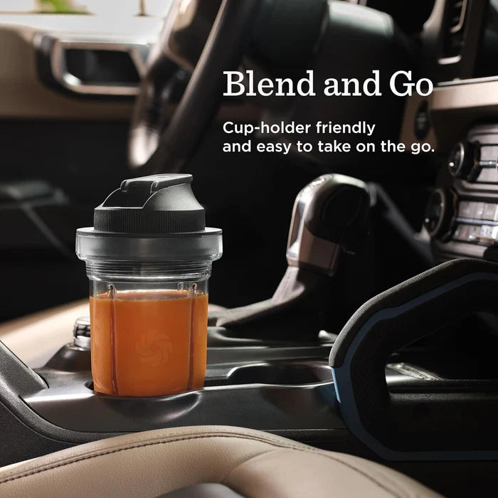 A clear shaker cup with a black lid sits in a car cup holder, filled with an orange drink. White text on the image reads 'Blend and Go' and 'Cup-holder friendly and easy to take on the go.