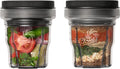 Two clear plastic blender cups with black lids, shown side by side on a white background. The left cup contains fresh vegetables including tomato, green pepper, and herbs, while the right cup contains dry spices and ingredients layered vertically.