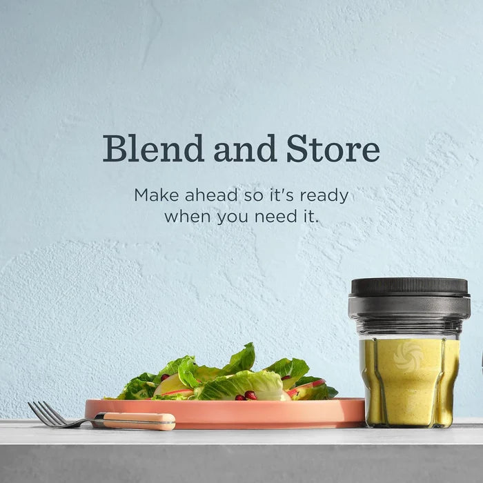 A glass blending jar with a black lid sits on a countertop beside a plate of salad, with the text 'Blend and Store' and 'Make ahead so it's ready when you need it.' above it against a pale blue textured wall.